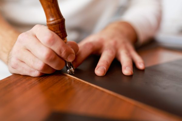 Master of leathercraft carrying out one of stages of wallet production